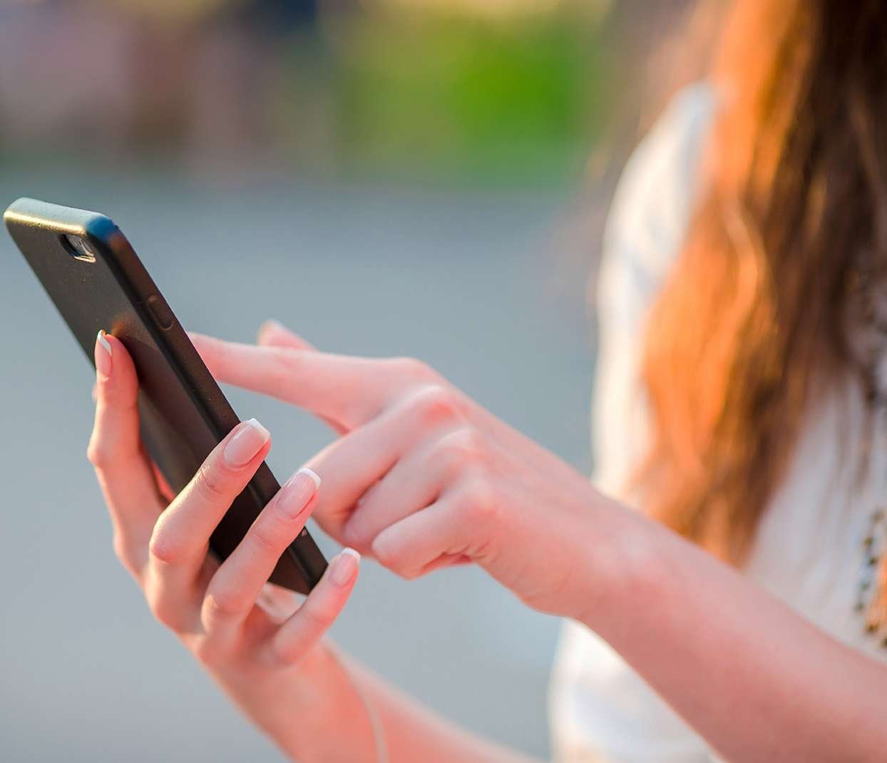 Closeup of female hands is holding cellphone in evening lights